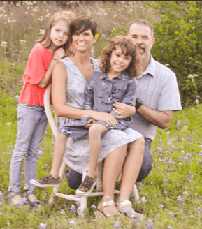 Husband and wife posing for a photo with their son and daughter.