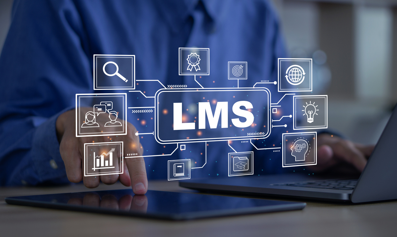 A person using a laptop and a tablet. Icons that represent aspects of a learning management system float in the air.