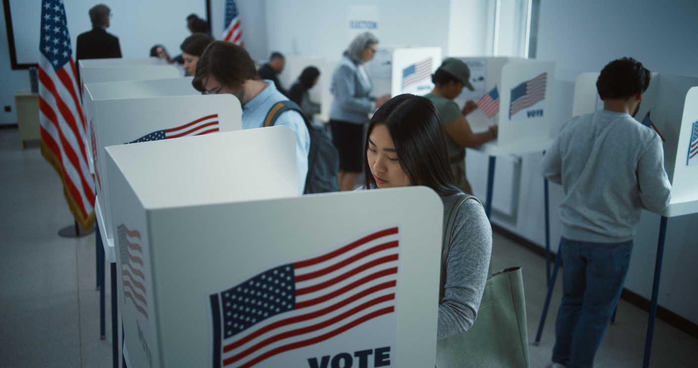 People voting in separate booths at a polling place.
