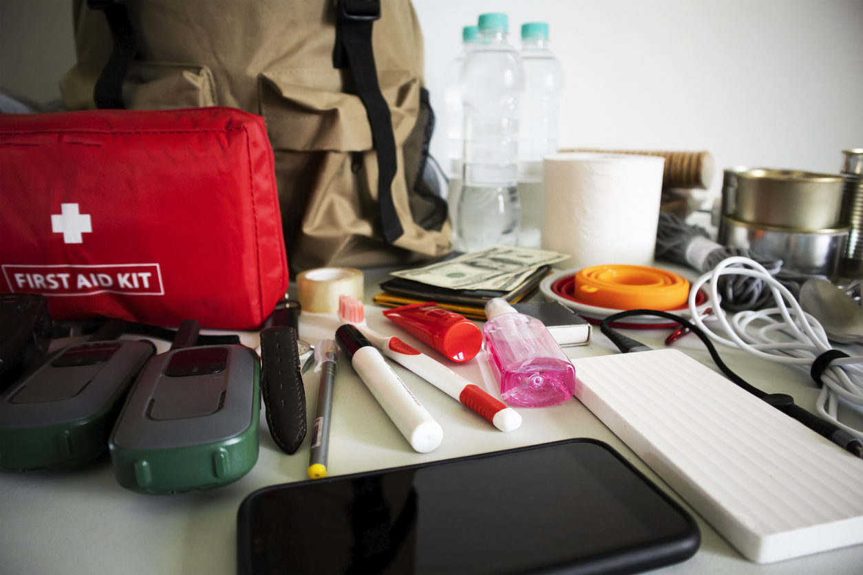 Assorted preparedness items, like a first aid kit, water, walkie talkies, and cash.